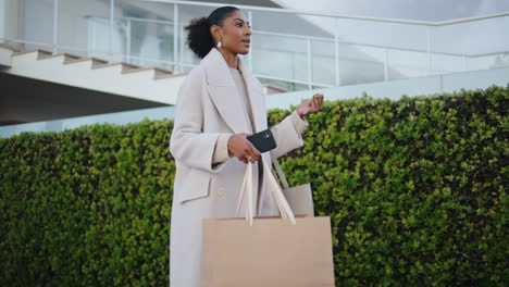 Elegant-woman-walking-street-with-shopping-bags.-Smiling-black-hair-girl-commute