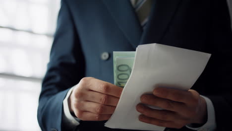 Man-putting-bribe-envelope-in-office-close-up.-Hands-placing-euro-for-corruption
