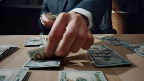 Hands-collecting-dollars-piles-at-desk-closeup.-Business-man-counting-banknotes.