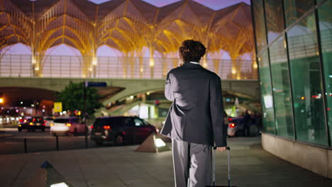 Businessman-having-phone-call-at-night-street.-Unknown-guy-carrying-baggage