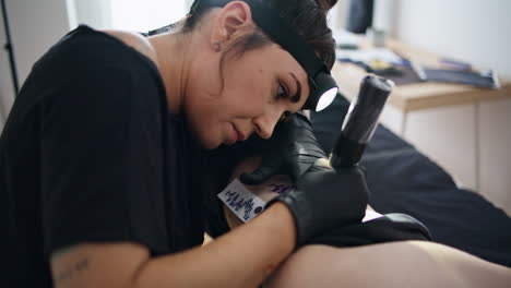 Professional-artist-tattooing-skin-salon-closeup.-Focused-woman-working-machine