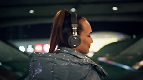 Bright-girl-walking-subway-in-headset-closeup.-Woman-listening-music-night-city