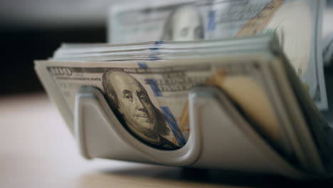 Counter-accumulating-money-cash-denomination-of-hundred-dollars-close-up.
