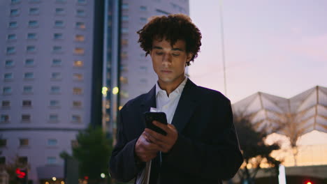 Handsome-businessman-swiping-phone-screen-sunset-city.-Young-startuper-texting