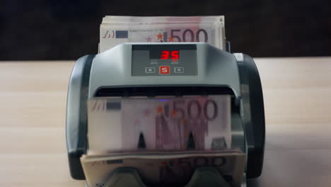 Euro-bills-counting-machine-close-up.-Man-hand-putting-currency-into-equipment.