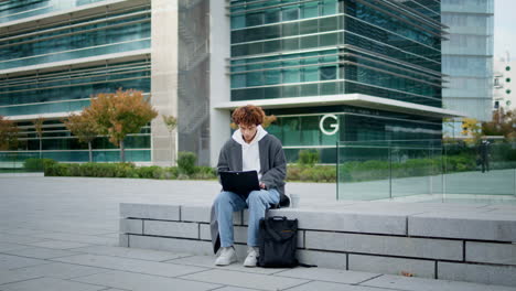 Focused-freelancer-typing-laptop-on-street.-University-student-learning-online