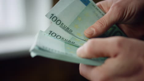 Hombre-Contando-Billetes-De-Cien-Euros-En-El-Interior-De-Cerca.-Manos-Calculando-Billetes.