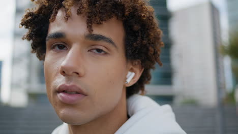 Young-man-speaking-wireless-earbuds-at-downtown-portrait.-Teenager-making-call