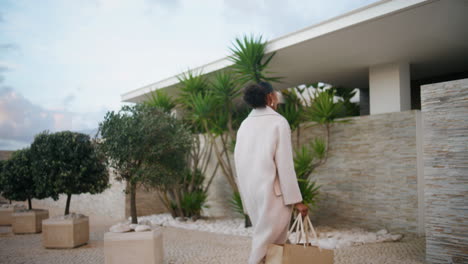 Woman-walking-modern-house-in-evening.-Stylish-african-american-entering-home