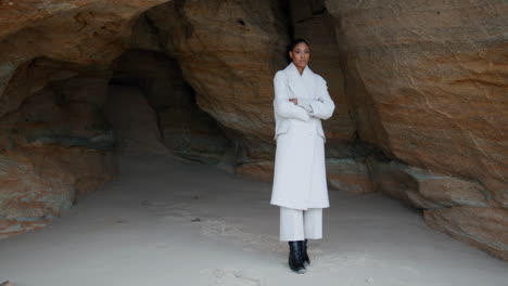 Unhappy-girl-thinking-troubles-at-seashore-cave.-Lonely-woman-with-crossed-hands