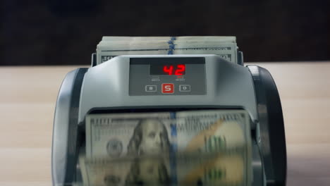 Closeup-counter-counting-dollar-bills.-Man-hand-putting-banknotes-into-equipment
