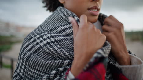Closeup-woman-chest-walking-windy-beach.-African-american-hands-adjusting-scarf