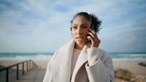 Mujer-Nerviosa-Hablando-Por-Teléfono-En-El-Primer-Plano-De-Ocean-Beach.-Serio-Afroamericano