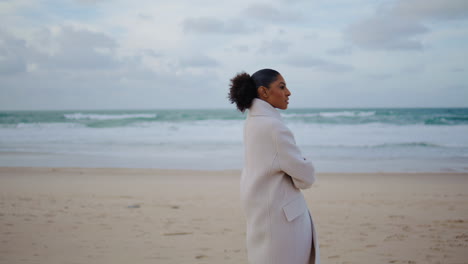 African-american-woman-strolling-ocean-shore.-Thoughtful-traveler-watching-waves