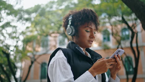 Girl-earphones-using-phone-app-to-listen-music-outdoor.-Woman-choosing-song.