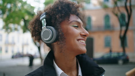 Positive-girl-listening-song-in-earphones-at-street-closeup.-Lady-enjoying-music