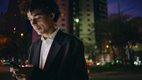 Relaxed-business-man-walking-cellphone-night-street-close-up.-Guy-texting-mobile