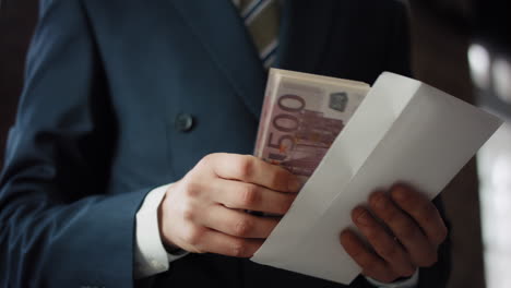 Hands-holding-bribe-envelope-containing-euro-cash-close-up.-Financial-crime.