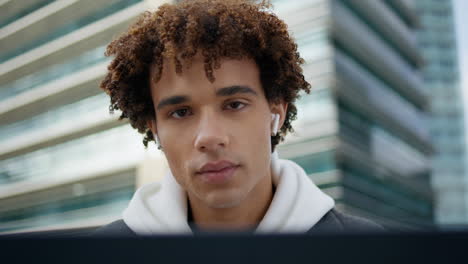 Earphones-youngster-using-laptop-computer-street-close-up.-Teen-looking-camera