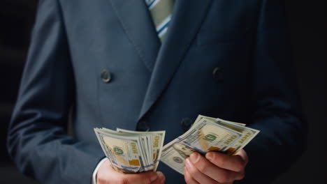 Rich-man-counting-profit-close-up.-Smart-businessman-calculating-dollar-bills.