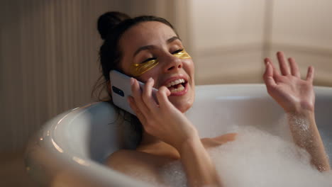 Spa-girl-laying-foam-laughing-mobile-phone-home.-Woman-enjoying-beauty-routine