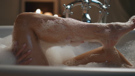 Woman-washing-foam-legs-in-bathtub-closeup.-Unknown-lady-chilling-at-bathroom