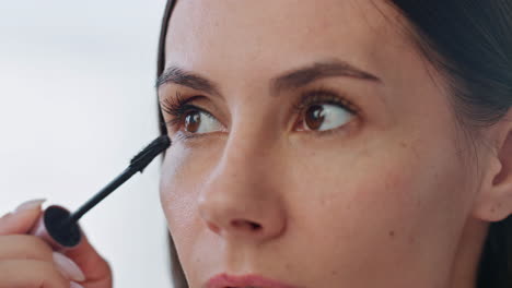 Serious-model-applying-mascara-indoors-closeup.-Focused-lady-putting-cosmetics