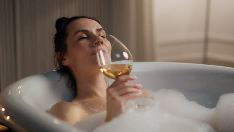 Serene-girl-sipping-alcohol-at-spa-room-closeup.-Relaxed-woman-taking-foam-bath