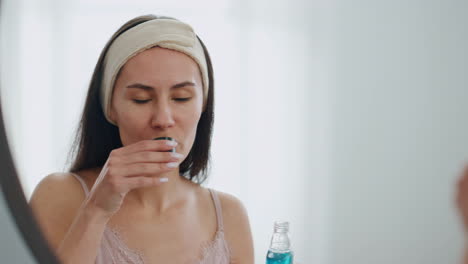 Happy-model-pouring-mouthwash-at-bathroom-close-up.-Smiling-lady-rinsing-mouth
