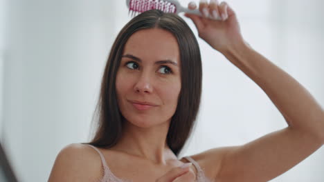 Satisfied-lady-brushing-hair-in-bathroom-closeup.-Woman-enjoying-beauty-routine