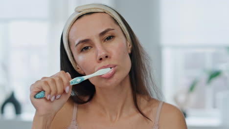 Awaking-woman-cleaning-teeth-at-bathroom-closeup.-Serious-lady-dental-hygiene