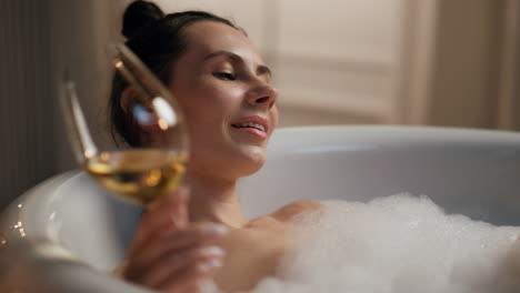 Carefree-girl-testing-alcohol-resting-bathtub-evening.-Lazy-woman-enjoying-spa