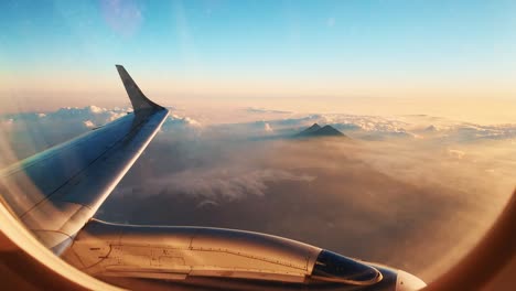 Aerial-View-of-Guatemala-Volcano-Peaking-Above-Heavenly-Clouds-During-Beautiful-Golden-Hour-Sunset-As-Seen-From-Airplane-Window-Seat