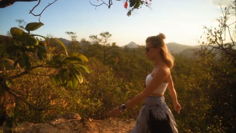 Beautiful-blond-European-woman-in-summer-clothes-is-walking-enjoying-the-beautiful-green-nature-of-Pai-Canyon-during-Golden-Hour-in-thailand