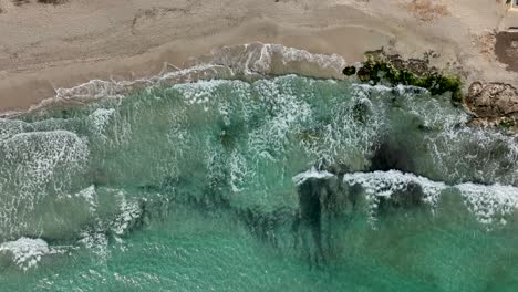 Top-down-view-of-waves-hitting-beach-in-slowmotion