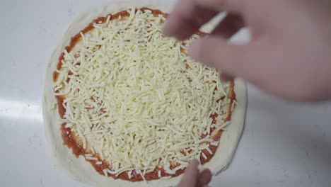 Top-down-view-of-sprinkling-mozzarella-on-a-traditional-margarita-pizza