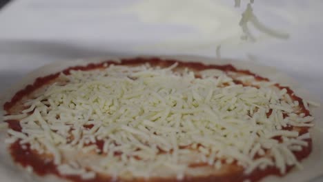 Sprinkling-mozzarella-cheese-on-a-traditional-margarita-pizza