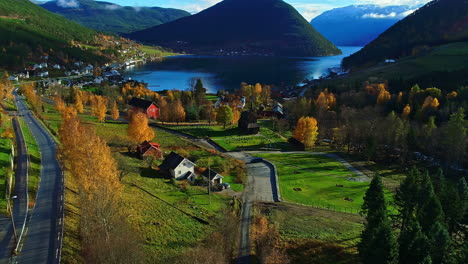 Drone-flying-towards-small-village-houses-in-Norwegian-fjords-in-sunny-day