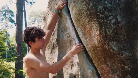 close-up-of-young-muscular-man-climbing-crag-boulder-shirtless-in-fontainebleau