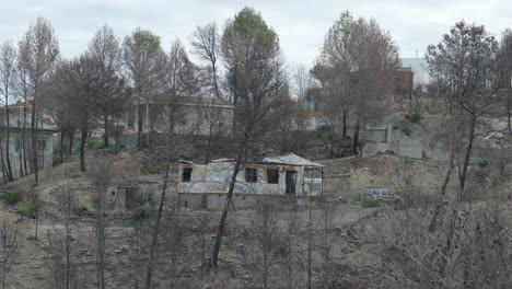 Observing-POV-across-burnt-remains-of-demolished-family-homes-after-forest-wildfire