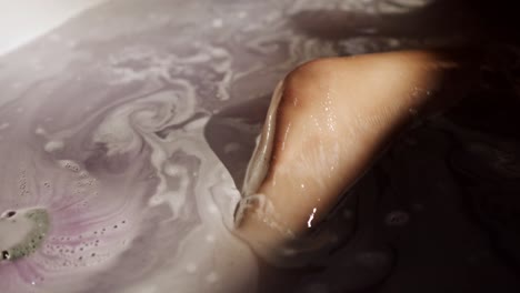 Close-up-of-woman-taking-a-bath,-bath-tub-full-of-water-with-soap-traces