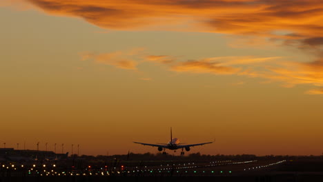 Silhouette-of-airplane-landing-at-airport-during-cinematic-sunset