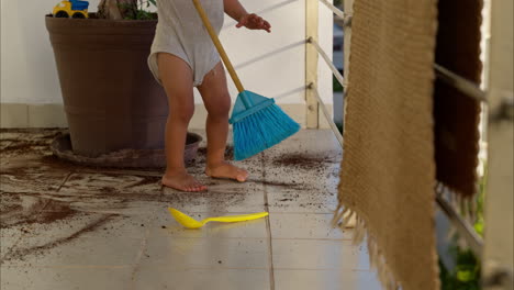 Little-latin-boy-playing-with-a-toy-broom-sweeping-dirt-from-the-floor-after-doing-a-mischief