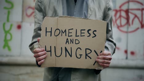 Man-is-holding-homeless-and-hungry-cardboard-sign,-homeless-concept