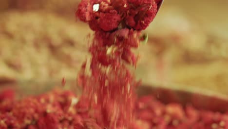 A-measuring-scoop-full-of-red-pink-dried-roses-being-poured-into-a-batch-of-dried-roses