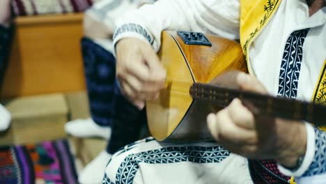 Man-in-ethnic-clothes-plays-folkloric-musical-instrument