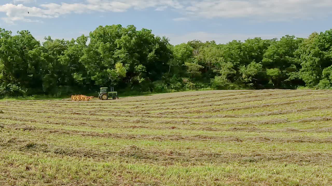 Premium stock video - Green tractor pulling hay rake through cut and ...