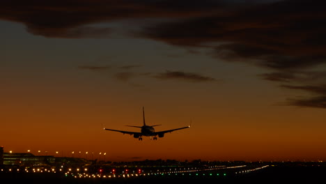 Silhouette-of-airplane-landing-at-Barcelona-airport-during-sunset