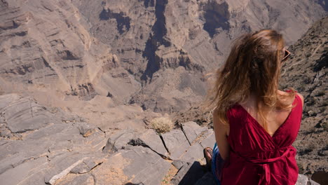 Western-traveler-girl-overlooking-Wadi-Ghul,-the-so-called-Grand-Canyon-of-the-Sultanate-of-Oman