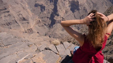 Western-traveler-girl-overlooking-Wadi-Ghul,-the-so-called-Grand-Canyon-of-the-Sultanate-of-Oman